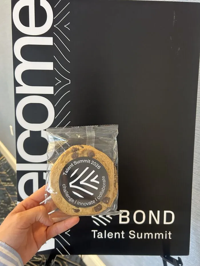 A branded Talent Summit cookie beside the Bond welcome board