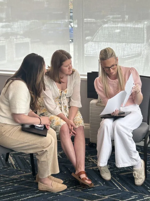 Three colleagues working through printed materials at the summit